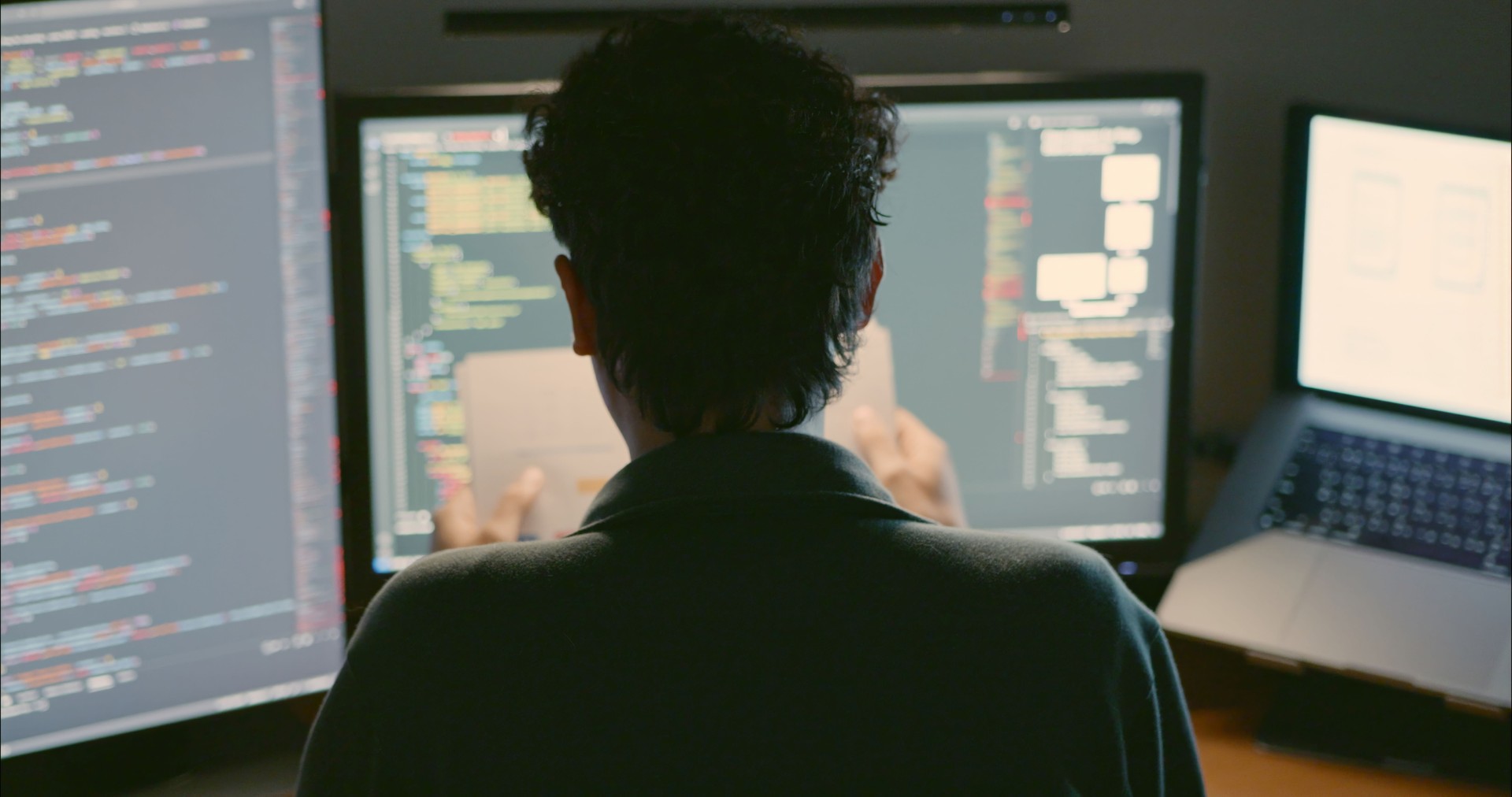 Developer Coding at Home Office with Multiple Screens.