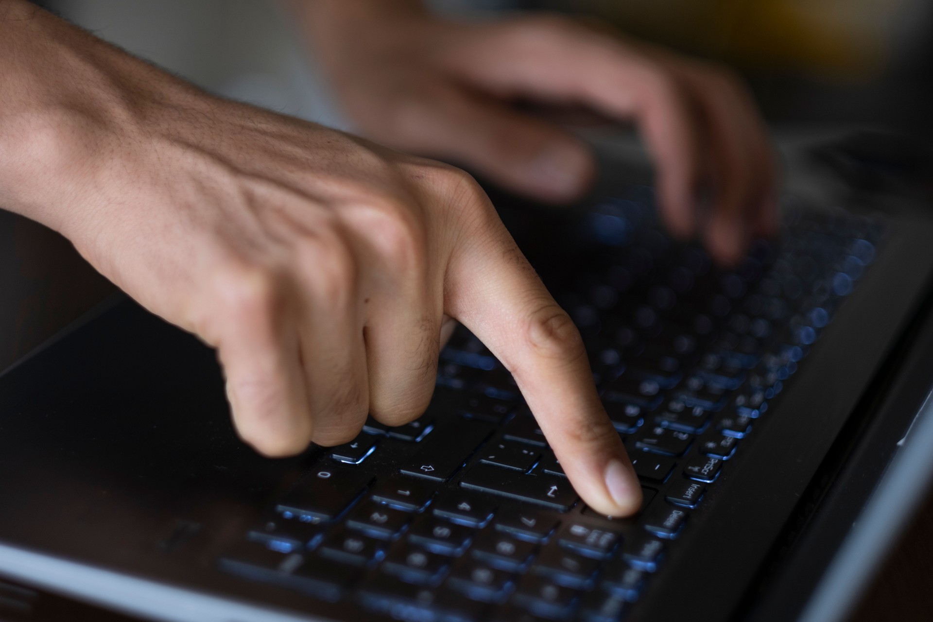 Programmer writing code on laptop keyboard in office